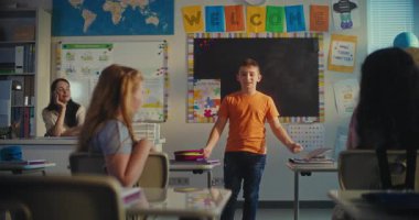 İlkokul çocuğu ekoloji bilgisini sınıfın önünde ve bayan öğretmen olarak gösteriyor. Sınıfta Masa başında oturan, Çevre Bilimleri Dersi sırasında konuşan kızlar. BTMM Eğitim. Sabit Çekim.