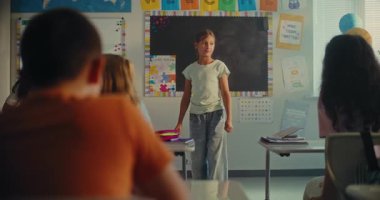 STEM Yenilenebilir Enerji Sınıfı: İlkokul kızı sınıf arkadaşlarının önünde ekoloji ödevini sunuyor ve bayan öğretmen. Sınıfta Fen Dersinde Masalarda Oturan Çeşitli Çocuklar.