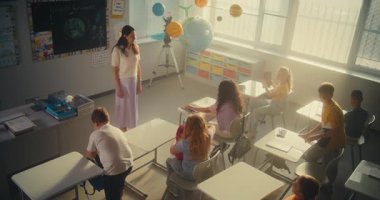 İlkokul çocukları derse hazırlanıyor, okul malzemelerini sınıftaki masalara diziyor. Okulun Başında Çeşitli Çocuklar Kadın Öğretmenler Grubu 'nu selamlıyorum. Ağır çekim. Yüksek Açı.