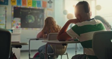 Modern Sınıfta Oturan ve Yenilenebilir Enerji Kaynakları Sınavı Yazan İlkokul Öğrencileri. Masaların Arasında Yürüyen Bayan Öğretmen, Okul Sınavı Sürecinde Genç Erkek ve Kızları Kontrol Etmek