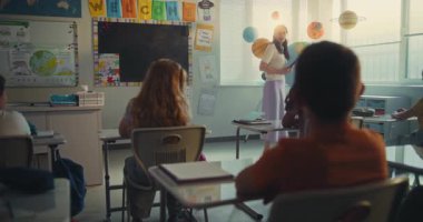 BTMM Yenilenebilir Enerji Sınıfı: Dijital Tabletle Kadın Öğretmen Çeşitli Çocuklara Ekoloji Eğitiyor. İlkokul çocuğu, sınıftaki Dünya Modelini Kullanarak Enerji Kaynaklarını Sunuyor. Doli Vuruşu.