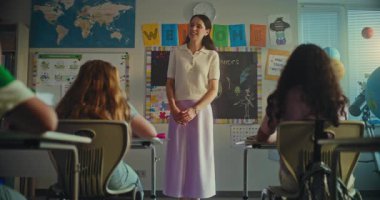 BTMM Yenilenebilir Enerji Sınıfı: İlkokul öğrencisini sunan Bayan Öğretmen. Utangaç akıllı çocuk konuşuyor, çeşitli çocuklarla dolu sınıfın önünde ekoloji sunumu yapıyor. Yavaş Hareket.