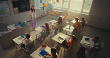 Modern Sınıfta Çevre Bilimi Dersinde Çocuklara Öğretmenlik Yapan Kadın Öğretmenler. Akıllı çocuklar el kaldırıyor, ilkokul öğrencisi kız sınıfın önünde ekoloji bilgisi gösteriyor. Yüksek Açı.