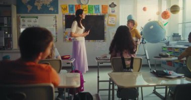 Bilim Dersi: İlkokul çocuğu, Yenilenebilir Enerji 'yi sunuyor Dünya Gezegeni' ni kullanıyor, Sınıfın Önünde Konuşuyor. Tablet Bilgisayarlı Kadın Öğretmen Zeki Çocuklara Ekoloji Eğitiyor. STEM Eğitimi.