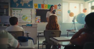 BTMM Yenilenebilir Enerji Sınıfı: Ekolojiyi Farklı İlköğretim Okulu Çocuklarına Eğiten Kadın Öğretmen. Yetenekli Kız Konuşması, Sınıf Arkadaşlarıyla dolu Sınıfın Önünde Ödev Sunumu. Doli Vuruşu.