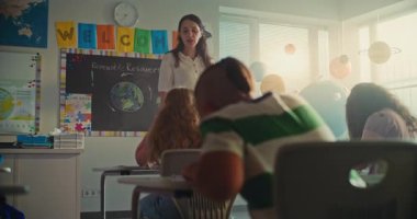 Modern Sınıfta İlkokul Çocukları Coğrafya veya Ekoloji Üzerine Okul Yazma Sınavı. Masalar Arasında Yürüyen Kadın Öğretmenler Sınav Sürecinde Çeşitli Çocukları Kontrol Etme Grubu. STEM Eğitimi.