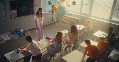 Bayan Öğretmen Dersi Bitiriyor, Okul Sonu 'nu Çeşitli Çocuklara Duyuruyor. İlkokul öğrencileri ayağa kalkıyor, sırt çantalarını topluyor ve Modern Sınıfı terk ediyor. Ağır çekim. Yüksek Açı