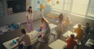 Bayan Öğretmen Dersi Bitiriyordu, Okul Günü 'nde Çeşitli Çocuklar Grubu' na veda ediyordu. Mutlu İlkokul çocukları sırt çantalarını topluyor ve tatil için okulu bırakıyor. Yüksek Açı.