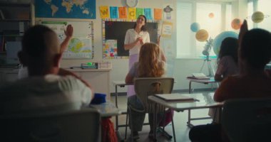 Çevre Bilimi Dersi: Ekoloji Eğitiminde Kadın Öğretmen. İlkokul çocukları el kaldırıyor, akıllı çocuk sınıfın önünde yenilenebilir enerji ödevini sunuyor. BTMM Eğitim. Yavaş Hareket.