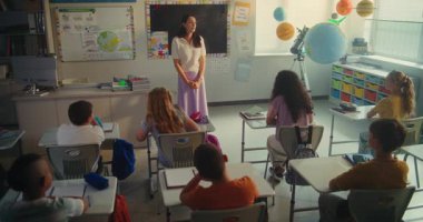 Çevre Bilimi Dersi: İlkokul çocukları el kaldırıyor. Bayan Öğretmen Oğlan ve Kızı Sınıfın Önünde Yenilenebilir Enerji Ödevi 'ni sundukları için kurula çağırıyor. STEM Eğitimi.