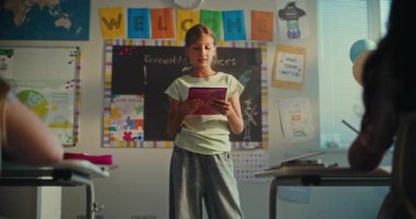 Modern Sınıfın Önünde Ekoloji Bilgisi ve Öğretmenini Gösteren Not Defteri 'ne sahip zeki ilkokul kızı. Çocuklar bilim dersi sırasında sunumdan sonra el çırpıyor. Doli Vuruşu.