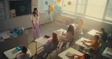 STEM Sınıfı: Ekolojiyi İlkokul Öğrencilerine Eğiten Kadın Öğretmenler Sınıfı. Çeşitli Çocuklar Cevap Vermek İçin Ellerinizi Kaldırın, Akıllı Kız Kurula Gidiyor ve Ödev Sunuyor. Yüksek Açı.