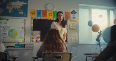 STEM Yenilenebilir Enerji Sınıfı: İlkokul öğrencisini kurula çağıran kadın öğretmen. Yetenekli çocuk, çeşitli çocuklarla dolu sınıfın önünde ekoloji ödevini sunar. Sınıf arkadaşları..