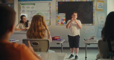 BTMM Yenilenebilir Enerji Sınıfı: İlkokul çocuğu sınıf arkadaşlarının önünde ekoloji ödevini sunuyor ve bayan öğretmen. Sınıfta Bilim Dersinde Masalarda Oturan Genç Erkekler ve Kızlar