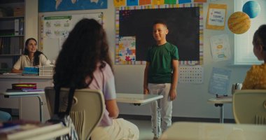 Modern Sınıfta Bilim Dersinde Genç Öğrenciyi Kurula Çağıran Bayan Öğretmen. İlkokuldaki Afro-Amerikan çocuk sınıfın önünde ekoloji bilgisi gösteriyor. STEM Eğitimi.