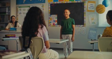 Modern Sınıfta Bilim Dersinde Genç Öğrenciyi Kurula Çağıran Bayan Öğretmen. İlkokuldaki Afro-Amerikan çocuk sınıfın önünde ekoloji bilgisi gösteriyor. STEM Eğitimi.