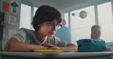 Hüzünlü ilkokul öğrencisi, sınıf arkadaşları ona zorbalık yaparken yalnız başına oturuyor ve ağlıyor, gülüyor ve kağıtları fırlatıyor. Okul zorbalığından, arkadaş tacizinden ve duygusal tacizden muzdarip.