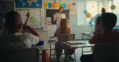 Çevre Bilimi Dersi: Ekoloji Eğitiminde Kadın Öğretmen. İlkokul çocukları el kaldırıyor, akıllı çocuk sınıfın önünde yenilenebilir enerji ödevini sunuyor. BTMM Eğitim. Yavaş Hareket.