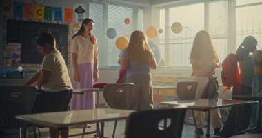 Bayan Öğretmen Dersi Bitiyor, Okul Sonu Günü 'nü Çeşitli Çocuklara Duyuruyor. İlkokul öğrencileri ayağa kalkıyor, sırt çantalarını topluyor ve Modern Sınıfı terk ediyor. Yavaş Hareket.
