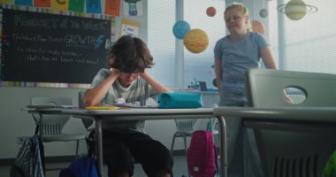 Hüzünlü ilkokul öğrencisi, sınıf arkadaşları ona zorbalık yaparken yalnız başına oturuyor ve ağlıyor, gülüyor ve kağıtları fırlatıyor. Okul zorbalığından, arkadaş tacizinden ve duygusal mücadeleden muzdarip.