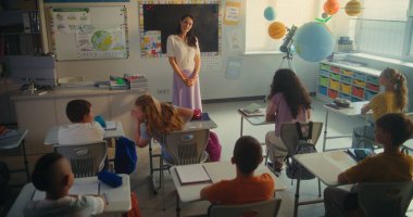 Çevre Bilimi Dersi: İlkokul çocukları el kaldırıyor. Bayan Öğretmen Oğlan ve Kızı Sınıfın Önünde Yenilenebilir Enerji Ödevi 'ni sundukları için kurula çağırıyor. STEM Eğitimi.