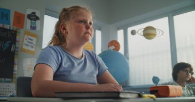 Agresif sınıf arkadaşları onu taciz ederken, Kağıtları fırlatırken ve gülerken, Sınıfta Tek Başına Oturan İlkokul Kızları. Okul zorbalığı, Akran Tacizi ve Toksik Okul Ortamı.