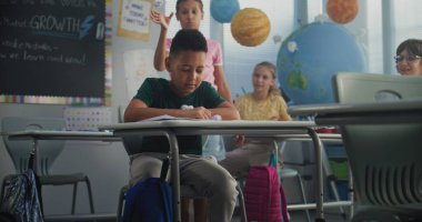 Saldırgan sınıf arkadaşları onu taciz ederken, kağıt fırlatırken ve gülerken yalnız başına masada oturan Afrika kökenli Amerikalı ilkokul çocuğu. Okul zorbalığı, ırksal taciz, Toksik Okul Ortamı.