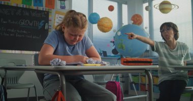 Sinir bozucu sınıf arkadaşları onu taciz ederken, Kağıtları fırlatırken ve gülerken, sınıf odasında yalnız oturan depresyondaki ilkokul kızı. Okul zorbalığı, Akran Tacizi ve Toksik Okul Ortamı.