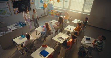 Modern Sınıfta Çevre Bilimi Dersinde Çocuklara Öğretmenlik Yapan Kadın Öğretmenler. Akıllı çocuklar el kaldırıyor, ilkokul öğrencisi kız sınıfın önünde ekoloji bilgisi gösteriyor. Yüksek Açı.