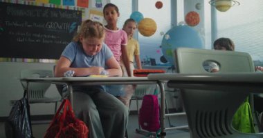 Sinir bozucu sınıf arkadaşları onu taciz ederken, Kağıtları fırlatırken ve gülerken, sınıf odasında yalnız oturan depresyondaki ilkokul kızı. Okul zorbalığı, Akran Tacizi ve Toksik Okul Ortamı.