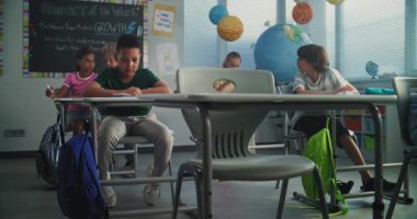 Depresyondaki Afrikalı Amerikalı İlkokul çocuğu, agresif sınıf arkadaşları onu taciz ederken, kağıtları fırlatırken, gülerken, masada tek başına oturuyordu. Okul Zorbalığı, Irksal Taciz ve Toksik Okul Ortamı.