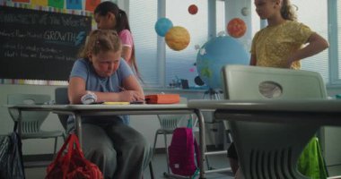 Hüzünlü ilkokul öğrencisi, sınıf arkadaşları ona zorbalık yaparken yalnız başına oturuyor ve ağlıyor, gülüyor ve kağıtları fırlatıyor. Okul zorbalığından, arkadaş tacizinden ve duygusal mücadeleden muzdarip kız.