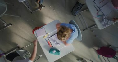 Sinir bozucu sınıf arkadaşları onu taciz ederken, Kağıtları fırlatırken ve gülerken, sınıf odasında yalnız oturan depresyondaki ilkokul kızı. Okul zorbalığı ve Toksik Okul Ortamı. Üst Görünüm Döndürülüyor.