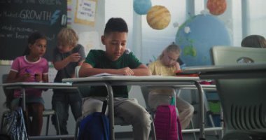 Saldırgan sınıf arkadaşları onu taciz ederken, kağıt fırlatırken ve gülerken yalnız başına masada oturan Afrika kökenli Amerikalı ilkokul çocuğu. Okul zorbalığı, ırksal taciz, Toksik Okul Ortamı.