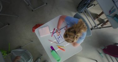 İlkokuldaki Kız Öğrenci Çizimi 'nin Okul Defteri' nde Dönen En İyi Görünümü. Çeşitli çocuklar ders öncesi eğleniyor ve oyun oynuyorlar. Okulda Etkileşimli Öğrenme ve BTMM Eğitimi.