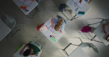 Modern Okuldaki BTMM Sınıfı 'nda Dönen Top View: Notebook' ta Yaratıcı İlkokul Kızı Çizimi Sınıfta. Ders öncesi sıralarda koşan, oynayan ve eğlenen okul çocukları