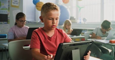 Sınıfta Dijital Tablet 'i kullanan ilkokul öğrencisi masada oturuyor. Dizüstü bilgisayarlar ve tablet bilgisayarlar üzerinde çalışan, Bilgisayar Bilimi, Temel Programlama ve Kodlama okuyan Zeki Çeşitli Çocuklardan oluşan Ekip.