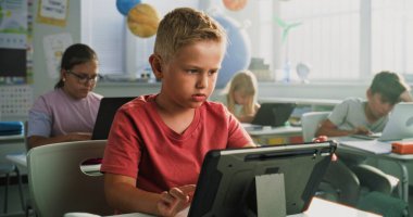 Sınıfta Dijital Tablet 'i kullanan ilkokul öğrencisi masada oturuyor. Dizüstü bilgisayarlar ve tablet bilgisayarlar üzerinde çalışan, Bilgisayar Bilimi, Temel Programlama ve Kodlama okuyan Zeki Çeşitli Çocuklardan oluşan Ekip.