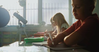 Resepsiyonda oturan ilkokul öğrencileri, Okul Sınavı veya Not Defterlerinde Ders Yazıyorlar. Modern Sınıfta Çevre Bilimi ve Coğrafya okuyan Zeki Çeşitli Çocuklar Sınavı.