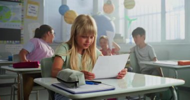 Resepsiyonda oturan ilkokul öğrencisi coğrafya veya fen sınavı notları konusunda mutlu. Neşelenen ve Kutlayan Zeki Çeşitli Çocuklar Takımı Mükemmel Okul Sınavı Renkli Sınıf Sonuçlarıyla Sonuçlandı.