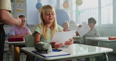 Modern Sınıfta Masalarda Oturan İlkokul çocuklarına Okul Sınavı Sonuçları Veren Öğretmenler. Coğrafya veya Fen Bilimleri Sınavı 'nda Mükemmel Notları Sevinen ve Kutlayan Zeki Genç Kız.