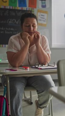 Boş Sınıfta Masada Tek Başına Oturan Yorgun Bayan Öğretmen Dersten Sonra Dinleniyor. Kadın Stres, Yakma ve Duygusal Mücadele, Modern İlkokulda Çalışmak. Dikey Çekim.