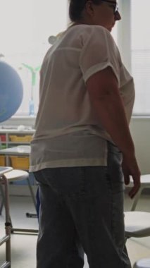 Boş Sınıfta oturan yorgun bayan öğretmen, dersten sonra dinleniyor. Eğitim Ortamı 'nda Kadın Stres, Burnout ve Zihinsel Yorgunluk İlkokulda Çalışıyor. Dikey Çekim.