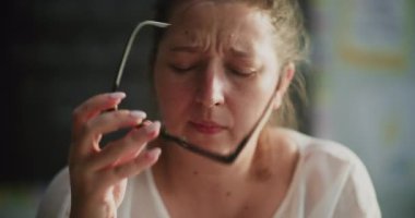 Yorgun kadın öğretmen gözlüğünü çıkarıyor, boş sınıfta tek başına oturuyor, dersten sonra dinleniyor. Öğretmen Stres Duyuyor, Yakıyor ve Duygusal Mücadele İlkokulda Çalışıyor. Görüntüyü Kapat.