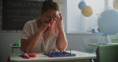 Boş Sınıfta Masada Tek Başına oturan Yorgun Bayan Öğretmen, Ders ve Zor Okul Günü 'nden sonra dinleniyor. Kadın Stres Duyuyor, Yanıyor ve Duygusal Mücadele Modern İlkokulda Çalışıyor.