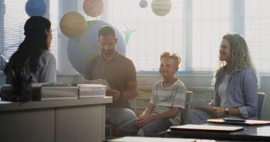 Anne ve baba, Veliler Gecesi 'nde Oğullarının Okul Sınav Notlarına Bakıyorlar. Öğretmen ve Aile Mükemmel Akademik Performans ve İlkokul çocuğunun Davranışından Mutludur. Orta Çekim.