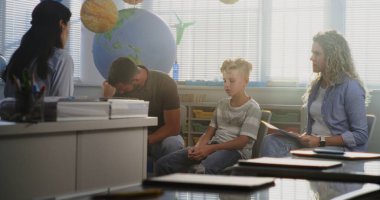 Oğullarının Sınav Notlarına Sınıfta Bakan Ebeveynler. İlköğretim Okulu Öğrencisinin Akademik Başarısızlığını Tartışan Öğretmenler ve Aileler Çözümleri Buluyor. Çocuk Gelişimini Desteklemek İçin Toplantı.