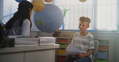 Bayan Öğretmen Okul Sınavını İlkokul Öğrencisine Sunar, Genç Çocukla Düşük Notlar ve Akademik Başarısızlık Tartışması. Çocukların Gelişmesini Desteklemek İçin Sınıf Arası Toplantı. Orta Çekim.