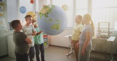 Çevre Bilimi Dersi: İlkokul çocukları konuşuyor, Dünya modeline bakıyor. Sınıfta Yetenekli Çocuklar Coğrafya, Ekoloji ve Yenilenebilir Enerji Kaynakları Öğreniyor. Etkileşimli BTMM Eğitimi