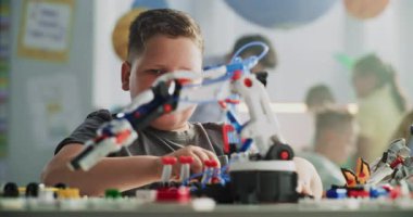 Masada oturan yetenekli genç çocuk, Erkek Öğretmenle Robotik Kol Modeli okuyor. Modern Sınıfta İlkokul Öğrenim Mühendisliği, Bilim ve Robot Teknolojisi. STEM Eğitimi.